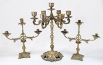 Conjunto de candelabros sacros, sendo um grande e pesado candelabro para 7 velas de altar em bronze fundido em peça única e dois castiçais para 3 velas em bronze dourado. Um deles com bobeche trocada. Brasil, séc.XIX. medida do maior: 48 x 36  e 35 x 36 cm.