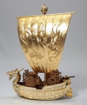 FENG SHUI - Escultura de barco chinês da Fortuna, Riqueza e Prosperidade em metal com banho de ouro. Proa no formato de cabeça de dragão. Velas decoradas com Fênix. Obs: Leme móvel. Med. 18 x 15 x 5 cm.