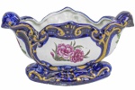 Belíssima Floreira, em fina porcelana, com rica policromia floral, arrematada por tons em azul. Dimensões: 13 cm X 27 cm X 13 cm (Alt./Comp./Larg.). lxxx