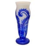 DEGUÉ  Vaso Art Déco em pasta de vidro acidado de formato alongado e levemente cônico, lavrado em cameo e ornamentado por folhagens e volutas estilizadas em azul Royal sobre fundo leitoso. Bojo abaulado encimado por gargalo retraído e borda suavemente revirada. Pé circular largo e liso. Assinado Degué no bojo e marca gravada Made in France sob a base. Criação da manufatura Verrerie dArt Degué, fundada em Paris pelo mestre vidreiro e artista espanhol David Guéron e ativa de 1926 a 1939. 41 x 14 cm.