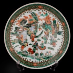 Medalhão de porcelana chinesa, apresentando esmaltes da Família Verde. Intensa decoração com personagens típicos com jardim e pagode. China. Séc. XIX. 30 cm. Apresenta sinais de uso.