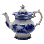 Bule para chá de louça inglesa conhecida como Borrão. Apresenta decoração em esmalte de tom azul cobalto sobre fundo branco com cena lacustre em jardim. Pega da pega na forma de pinha. Alça apresentando curvas e contra curvas. No fundo marca da manufatura: Indianak. 24 x 29 cm.