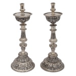 Par de tocheiros de prata batida, repuxada e alisada. Base cônica lavrados por folhagens e concheados, fuste abalaustrado e cinzelado por guirlandas em volutas e frisos sinuosos. Bobeches semicirculares cinzeladas por representações vegetais. Brasil. Séc. XVIII. 43 cm. 3k500g.