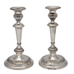 Par de castiçais de prata portuguesa repuxada e cinzelada, ornamentados por faixas de gomos e frisos florais. Hastes construídas em segmentos de balaústre, encimadas por bobeches abauladas com bordas peroladas. Bases circulares almofadadas. Contrastes da cidade do Porto, P Coroa atribuíveis a António José de Sousa, usados entre 1818-1836 e marcas do prateiro Manuel António da Silva, citado em 1822. (Moitinho, P-26 p.192 e P-443 p.269). 23.5 cm (altura). 12 cm (diam. da base). Peso: 799 gramas.