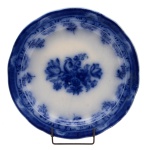 Travessa circular e borda ondulada em louça inglesa, conhecida como borrão. Superfície de fundo branco e decoração em tom de azul cobalto. Centro com ramo florido e borda com flores. No verso marcas da manufatura e as inscrições: England. Copeland, Circa de 1850. Encyclopedia of British Pottery Marks Flower Blue. 32 cm.