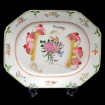 Travessa retangular chanfrada de porcelana Companhia das Índias ornamentado em esmaltes policromados da Famille Rose. Borda decorada com flores e frutas alternadas por estilizações. Centro ornado com rolos de pinturas florais ladeados por romãs. China. Dinastia Qing (1644 - 1911). Qianlong (1736-1785). 41 x 33 cm.