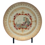Prato em porcelana chinesa da Companhia das Índias, decorado em esmaltes da Família Rosa no padrão Meissen. Bordas estilizadas a ouro centralizando reserva com adornos florais e paisagem com personagens europeus. No verso, etiqueta da Coleção Noronha. China, Qing, Qianlong (1736-1795). Séc. XVIII. 31 cm.