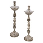 Par de castiçais em prata brasileira, repuxada e cinzelada, ornamentados por frisos perolados e adornos barrocos cinzelados. Hastes construídas com segmentos de balaústre e anelados. Bobeches semi globulares encimadas por ponteiras. Bases quadrangulares recortadas e chanfradas. Pseudo contrastes da cidade Porto da 2ª metade do século XIX e marcas de prateiro não identificado, porém repertoriado (Moitinho BR-92D, p.368). 53 cm.
