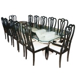Conjunto de mesa para jantar com 12 cadeiras, sendo 2 com braços. Mesa com tampo de cristal bizotado de 15 mm apoiado em duas bases em resina artesanal, assinada Rocha. Cadeiras em madeira com acabamento em laca preta. 75 x 300 x 75 cm (medida a mesa)