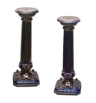 Par de colunas em porcelana azul cobalto, assentadas em base quadrada, com cantos recortados, enovelados em folhas de acanto em relevo, ornamentadas em dourado intenso nas bordas. Tampo redondo e fuste cilíndrico canelado, em bela torção. 76 x 29 x 29 cm.