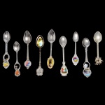 Conjunto de 9 colheres de metal prateado com decoração e materiais variados. 12 cm (maior). 11 cm (menor).