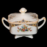 Açucareiro de louça inglesa. Apresenta formato quadrangular com decoração floral com detalhes em dourado e azul sobre fundo branco.  No fundo marca da manufatura J. & G Meakin. England. 10 x 14 x 10 cm.