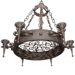 Lustre em ferro construído com coroa central ladeada por seis pares de volutas, sustentando castiçais no formato de corneta com bordas lobuladas. Fundo ornado e vazado com arabescos. Correntes laterais reunidas a colar com arremate de sustentação e argola no topo. Pertenceu ao acervo do castelo de Itaipava. 76 x 63 cm.