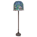 Luminária Art Déco de pé alto em bronze patinado. Haste no formato de coluna anelada lisa, apoiada em base circular abobadada ornada por friso floral vazado. Cúpula semi esférica  construída com placas de vidro policromadas, ornamentada por flores distribuídas em reservas bordadas por finos frisos verticais. 162 x 50 cm.