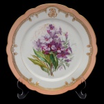 Prato circular de porcelana francesa. Borda ondulada com faixa na cor salmão e detalhes em ouro. Iniciais entrelaçadas em reserva. Centro com decoração de flores e folhagens. No verso marca da manufatura CH. Pillivuyt & Cie  Paris. Exp. 1867. Medalle Dor. 22 cm.