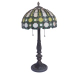 Luminária de mesa para duas luzes com estrutura em bronze. Haste moldada no formato de coluna ornada com folhagens, apoiada em base circular bordada por friso floral. Cúpula abobadada com armação geométrica realçada por frisos verdes e pequenos cabochões vermelhos, ornamentada por placas em vidro marmorizado em tons de bege e amarelo. Topo pontudo rematado por pião. 62 x 30 cm. Este lote encontra-se em Belo Horizonte, MG, e só estará disponível em nossa loja a partir do dia 13 de Outubro.