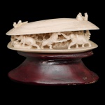 Pequena escultura chinesa em marfim no formato de concha meio aberta, revelando interior esculpido com cena apresentando luta de elefantes e leões. Sobre a concha, pequenas figuras sentadas. Acompanha peanha em madeira.  3 x 7 cm / base 2 x 7 cm. Este lote encontra-se em Belo Horizonte, MG, e só estará disponível em nossa loja a partir do dia 13 de Outubro.