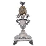 Paliteiro em prata portuguesa repuxada e cinzelada, ornamentado por frisos florais. Apresenta vaso com alças encimado por abacaxi, apoiado em anelados lisos. Base quadrangular com pés recurvos rematados por volutas. Contraste de Lisboa datável de c.1843  c.1870 e marca de prateiro ilegível. 17 x 8 x 8 cm. Peso 207 gramas.