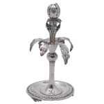 Paliteiro em prata brasileira repuxada e cinzelada. Apresenta haste tubular lisa encimada por bolota e folhagens recortadas em leque, centralizando botões florais com pequena fruta no topo. Base esparramada sobre pequena salva circular, ornada por friso estilizado e pés retos. 14 x 7 cm. Peso 113 gramas.