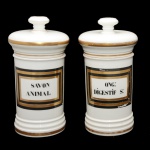 Par de potes de farmácia de porcelana francesa. Superfície branca apresentando rótulo com as inscrições: SAVON ANIMAL e ONG: DISGESTIF S: envolto em moldura dourada e preto. França. Séc. XX. 26 cm.