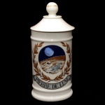 Pote de farmácia em porcelana francesa de formato cilíndrico, com tampa cônica rematada por bolota. Bojo moldado com frisos anelados, ornamentado por reserva policromada representando paisagem com luar, assinada e com a inscrição Pierre de Lune ladeada por folhagens. Sob a base, marcas da manufatura de Limoges Au Pot de Gallien, exemplar No 006 de uma edição limitada de 1500 peças com assinatura de Paulette et Jean Louis Labourel. Séc. XX. 26.5 cm.