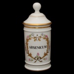 Pote de farmácia em porcelana francesa de formato cilíndrico, com tampa cônica rematada por bolota. Bojo moldado com frisos anelados e filetes dourados, ornamentado em policromia com guirlanda floral. Traz a inscrição Arsenicum. Sob a base, marcas da manufatura de Limoges, France Au Pot de Gallien e Produits Dentaires Biodica. Séc. XX. 28 cm.