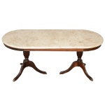 Mesa de centro de madeira apresentando tampo de mármore de forma ovalada, apoiado em duas pernas torneadas de onde saem três pés. Séc. XX. 45 x 110 x 50 cm. Lote pertencente ao acervo de tradicional família paulistana de Américo Moreira dos Santos e Anella Mafalda Malzoni. Este lote encontra-se na residência em SP e a retirada devera ser feita a partir do endereço com a orientação da organizadora do leilão.
