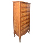 Semainier, estilo Louis XV, em madeira nobre ornamentado por painéis recortados em rádica cor de mel. Caixa reta com 7 gavetas superpostas, encimadas por tampo retangular com quinas chanfradas. Ilhargas seguindo a mesma decoração. Saia inferior ondulada apoiada em pernas curvilíneas. Ferragens em bronze ormolu. Séc. XX. 146 x 71 x 39 cm. Lote pertencente ao acervo de tradicional família paulistana de Américo Moreira dos Santos e Anella Mafalda Malzoni. Este lote encontra-se na residência em SP e a retirada devera ser feita a partir do endereço com a orientação da organizadora do leilão.