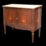 Cômoda estilo francês Louis XVI, ornamentada em marqueterie com vasos de flores em reservas ovais. Tampo retangular em mármore bege apoiado em caixa reta. Frente com par de portas ladeadas por colunatas filetadas. Interior com prateleiras. Ilhargas reproduzindo a mesma decoração. Saia ondulada sustentada por pernas retas no formato de colunas caneladas e aneladas. 86 x 98 x 42 cm. Lote pertencente ao acervo de tradicional família paulistana de Américo Moreira dos Santos e Anella Mafalda Malzoni. Este lote encontra-se na residência no Ibirapuera, SP e a retirada devera ser feita a partir do endereço com a orientação da organizadora do leilão.