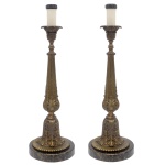 Par de tocheiros em bronze polido, de formato reto, moldados e ornamentados por folhagens e frisos. Hastes construídas em segmentos de balaústre e anelados, encimadas por bobeches com bordas reviradas. Bases com perolados, assentadas sobre peanhas circulares em granito. 56 x 17 cm. Lote pertencente ao acervo de tradicional família paulistana de Américo Moreira dos Santos e Anella Mafalda Malzoni.