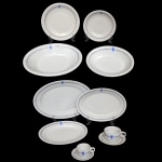 Remanescente de um serviço para jantar de porcelana nacional. Superfície branca com friso na cor azul e dourado ladeados por brasão azul. No fundo marca da manufatura Porcelana Teixeira. São Paulo. Made in Brazil. Constando de 25 peças, sendo: 3 pratos rasos (24 cm), 5 pratos fundos (20 cm), 6 pratos para sobremesa (18 cm), 3 travessas ovais ( 23 x 36 cm / 20 x 30 cm / 18 x 26 cm), 2 travessas ovais fundas (6 x 21 x 29 cm / 4 x 18 x 23 cm), 3 xícaras com pires p/ chá (6 x 11 cm / 14 cm), 3 xícaras com pires p/ café (5 x 8 cm / 10 cm). Lote pertencente ao acervo de tradicional família paulistana de Américo Moreira dos Santos e Anella Mafalda Malzoni.
