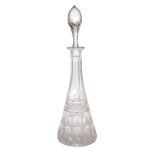 Licoreiro de cristal da Boêmia de formato cônico, lapidado e ornamentado por suaves gomos atravessados por friso com adornos estrelares. Gargalo longo lavrado em gomos e borda revirada. Tampa piriforme e fundo com estrela facetada. Tampa com leve bicado na ponta. 43 cm. Lote pertencente ao acervo de tradicional família paulistana de Américo Moreira dos Santos e Anella Mafalda Malzoni.