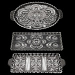 Conjunto com três petisqueiras de cristal translúcidos. Duas apresentando formato retangular e lapidações na forma de estrelas e florais. 34 x 15 cm / 34 x 13 cm. Uma de formato oblongo acompanhando a mesma decoração. 4 x 35 x 22 cm. Lote pertencente ao acervo de tradicional família paulistana de Américo Moreira dos Santos e Anella Mafalda Malzoni.