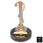 MFS  Porta caneta executado em liga metálica envolto em cobra de metal dourado. Base circular de bronze com pequenas pedras semipreciosas de cor verde. Apoio para a caneta e a placa de identificação Medicina. 15 x 9 cm. Peça nova, sem uso. MFS tradicional fabricante de joias de elevado padrão de qualidade, reuniu técnica, talento e beleza artesanal. A experiencia e o pioneirismo no ramo joalheiro permitiram a criação de Produtos Finos para presentes que possuem componentes banhados a ouro 14 Quilates e as cores são resultado do aprimoramento da técnica revestida a fogo e da qualidade MFS. 15 x 9 cm. Lote pertencente ao acervo de tradicional família paulistana de Américo Moreira dos Santos e Anella Mafalda Malzoni.