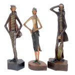 Conjunto de três estatuetas em madeira policromada representando dois marinheiros e uma moça. Nota-se a natureza humorística dos personagens na expressividade de suas feições e atitudes, sutilmente expressas pelo escultor. Bases lisas com assinaturas do autor provavelmente N. Bras. 49 cm. Apresenta sinais do tempo e falta de matéria. Lote pertencente ao acervo de tradicional família paulistana de Américo Moreira dos Santos e Anella Mafalda Malzoni.