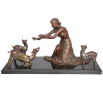 Grupo escultórico em bronze patinado em tonalidades diversas, representando jovem moça ajoelhada brincando com cabras. Base retangular lisa em granito preto. 25 x 46 x 18 cm. Base apresentando quebrado em uma das pontas. Lote pertencente ao acervo de tradicional família paulistana de Américo Moreira dos Santos e Anella Mafalda Malzoni.