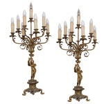 Par de candelabros em bronze dourado para 8 lampâdas em formato de velas. Hastes construídas com estatuetas representando anjos de pé segurando galhos floridos, sustentando braços recurvos e ponteiras, rematadas por bobeches com bordas lobuladas. Bases com pequenos pedestais apoiados em pés revirados. 94 x 43 cm. Lote pertencente ao acervo de tradicional família paulistana de Américo Moreira dos Santos e Anella Mafalda Malzoni.