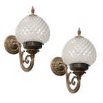 Par de apliques de parede em bronze dourado e cristal, construído com globos cônicos lapidados em bico de jaca e sustentados por braços recurvos. Hastes no formato de S realçadas por folhagens, rematadas a suportes circulares lavrados com florões. 37 x 30 cm.  Lote pertencente ao acervo de tradicional família paulistana de Américo Moreira dos Santos e Anella Mafalda Malzoni. Este lote encontra-se na residência no Ibirapuera, SP e a retirada devera ser feita a partir do endereço com a orientação da organizadora do leilão.