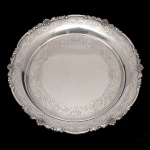 Salva funda em prata portuguesa repuxada e cinzelada. Borda larga, ornamentada por volutas, ramos floridos, drapeados, folhagens e treliças vazadas. Fundo gravado com adornos florais. Contraste do Porto Javali 2º Título e marca de prateiro. 20 cm. 286 gramas. Lote pertencente ao acervo de tradicional família paulistana de Américo Moreira dos Santos e Anella Mafalda Malzoni.
