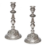 Par de pequenos castiçais de metal prateado. Base circular. 19 cm. Lote pertencente ao acervo de tradicional família paulistana de Américo Moreira dos Santos e Anella Mafalda Malzoni.