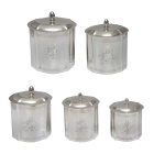 Conjunto com cinco potes para chá de metal prateado. Apesenta formato ovalado com decoração de um leão em pé coroado. Pega da tampa na forma de pinha. No fundo marcado Shefield Plate. 20 x 15 x 14 cm (maior). 13 x 1 x 1 cm (menor). Lote pertencente ao acervo de tradicional família paulistana de Américo Moreira dos Santos e Anella Mafalda Malzoni.