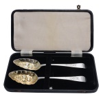 Par de Silver Fruit Spoons, colheres para servir salada de frutas, em prata inglesa georgeana repuxada e cinzelada. Bojos com resquícios de vermeil. Cabos recortados e gravados com adornos florais. Contrastes de Londres de 1803 e marcas do prateiro William Sumner I. Acompanha estojo original forrado em veludo preto. 22 cm. 4 x 26 x 14 cm (estojo). Lote pertencente ao acervo de tradicional família paulistana de Américo Moreira dos Santos e Anella Mafalda Malzoni.