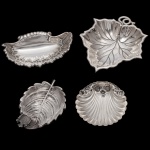 Conjunto de 4 porta petiscos em metal prateado repuxada e cinzelada, moldados no formato de folhas e conchas. Conchas: 7 x 7 cm), (10 x 7 cm). Folhas (9 x 6 cm) (11 x 10 cm). Lote pertencente ao acervo de tradicional família paulistana de Américo Moreira dos Santos e Anella Mafalda Malzoni.