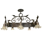 Lustre em metal escurecido, ornado por ramos e folhagens. Centro de formato retangular longo ladeado por três pares de braços recurvos, rematados por tulipas em vidro leitoso com bordas onduladas. Parte superior construída com volutas encimadas por anelado. 56 x 101 x 106 cm.  Lote pertencente ao acervo de tradicional família paulistana de Américo Moreira dos Santos e Anella Mafalda Malzoni. Este lote encontra-se na residência no Ibirapuera, SP e a retirada devera ser feita a partir do endereço com a orientação da organizadora do leilão.