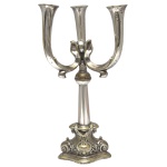 Candelabro para três velas de metal prateado. Base triangular com decoração barroca. Coluna central sustentando dois braços curvos. No estado. 40 x 23 cm.  Lote pertencente ao acervo de tradicional família paulistana de Américo Moreira dos Santos e Anella Mafalda Malzoni.