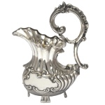 Jarra para água de metal prateado apresentando formato navicular. Alças sinuosas com curvas e contras curvas. No fundo marcado Sheffield Plate. 26 x 19 x 10 cm.  Lote pertencente ao acervo de tradicional família paulistana de Américo Moreira dos Santos e Anella Mafalda Malzoni.