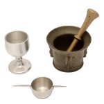 Lote constando de duas peças, sendo: A) Pilão com socador em metal dourado. 16 cm e 11 cm(socador. B) Provador de bebidas composto por cálice (10 cm) e dosador (3 x 13 cm). Lote pertencente ao acervo de tradicional família paulistana de Américo Moreira dos Santos e Anella Mafalda Malzoni.