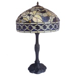 Luminária de mesa Art Déco em bronze patinado. Haste moldada com estilizações vegetais, apoiada em base recortada por friso floral. Cúpula abobadada, construída com placas de vidro em tons azul e marfim formando motivos florais, realçada por cabochões em pedraria. Borda circular reta com friso geométrico seguindo a mesma decoração. 68 x 39 cm. Este lote encontra-se em Belo Horizonte, MG, e só estará disponível em nossa loja a partir do dia 13 de Outubro.