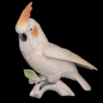 Estatueta em porcelana alemã policromada representando cacatua sobre tronco. No fundo marca da manufatura EPNS. 16 cm. Este lote encontra-se em Belo Horizonte, MG, e só estará disponível em nossa loja a partir do dia 13 de Outubro.