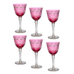 Conjunto de seis taças para vinho em cristal europeu de tonalidade rosácea. Ornamentado com lapidações de cachos de uva e folhas de videira, entre faixas geométricas. Bojo em formato piriforme com longo gargalo rematado com facetas picotadas. 17 cm